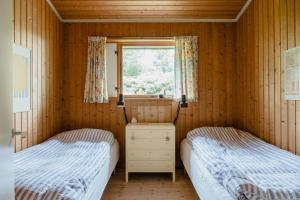 two beds in a wooden room with a window at Warm 70S Vibe Near Limfjord in Løgstør