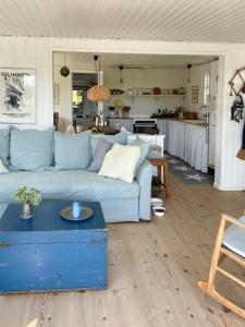 a living room with a blue couch and a kitchen at Charming Summer House Near Dalbybugten in Mesinge