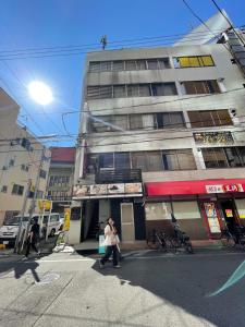 Eine Frau überquert eine Straße vor einem Gebäude in der Unterkunft Sidihome Cocosia House in Osaka