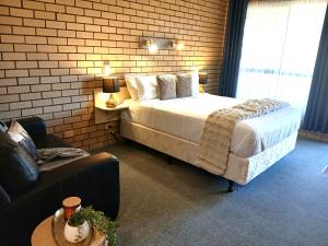 a bedroom with a bed and a chair and a couch at Birch Motel Tocumwal Previously Known as Kanimbla Motor Inn in Tocumwal