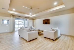 uma sala de estar com duas cadeiras brancas e um sofá em Sunny Tropicana Cape Coral em Cape Coral