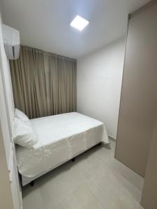 Apartamento Canto do Forte في برايا جراندي: غرفة نوم صغيرة بها سرير ونافذة