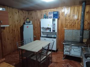 a kitchen with a table and a white refrigerator at Casa Familiar Equipada in Curacautín