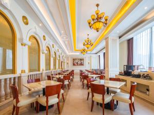 长沙Vienna International Hotel Changsha BBK Meixi Xintiandi Branch的有桌椅和枝形吊灯的餐厅