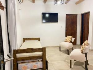 a bedroom with two beds and a chair and a tv at Dulces Parrales - Cabañas en San Rafael, Mendoza in San Rafael