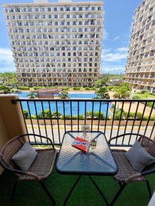 a table and chairs on a balcony with a view of a building at Pure Bliss Getaway Condo Near Mactan Airport Lapu-Lapu in Lapu Lapu City