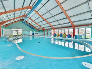 a large indoor swimming pool with blue water at Harbour Haven - Hayling Island in South Hayling