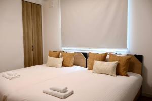 een slaapkamer met een bed met twee handdoeken erop bij New open 岸里玉出 Maison Le Jaune 玉子心斋桥道顿崛电车直达 in Osaka