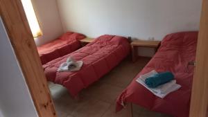 three beds in a room with red sheets and towels at Cabañas Mi Viejo in El Hoyo