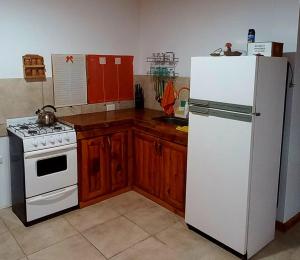 a kitchen with a white refrigerator and a stove at Cabañas Mi Viejo in El Hoyo