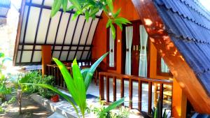 a house with a porch with plants in front of it at Ina Gili Guesthouse in Gili Islands