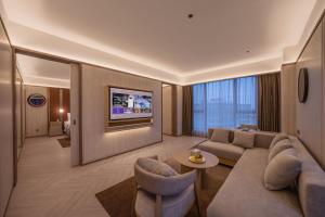 a living room with a couch and chairs and a tv at Orange Crystal Beijing Capital Airport New International Exhibition Hotel in Beijing