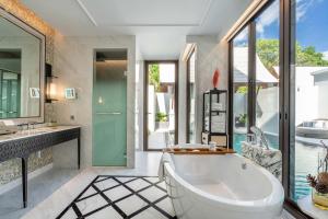 a bathroom with a tub and a sink and a mirror at InterContinental Phuket Resort by IHG in Kamala Beach