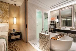 a hotel room with a bed and a tub and a bathroom at InterContinental Phuket Resort by IHG in Kamala Beach