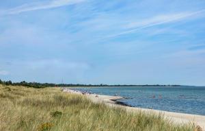 a beach with a bunch of people swimming in the water at 1 Bedroom Awesome Home In Væggerløse in Marielyst