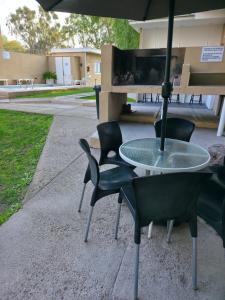 a table and chairs with an umbrella on a sidewalk at Complejo Turístico Mendoza in Godoy Cruz