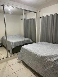 a bedroom with two beds and a mirror at Apto Completo com Cozinha Equipada in Valparaíso de Goiás