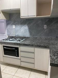 a kitchen with white cabinets and a stove top oven at Apto Completo com Cozinha Equipada in Valparaíso de Goiás