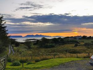 a car parked on a road in a field with the sunset at Cuillin View Apartment - Uk12529 in Arisaig