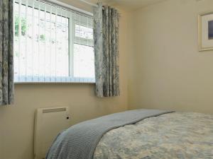 Un dormitorio con una cama y una ventana con cortinas. en Gone Sailing, en Windermere 7 fotos más