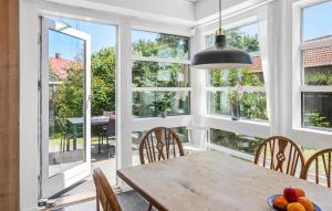 a dining room with a table and chairs and windows at Lovely Home In Væggerløse With Wifi in Marielyst