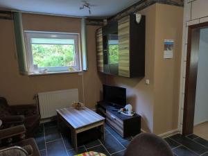 a living room with a table and a tv at Ferienhaus Waldperle Harzblick in Wernrode