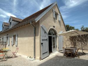 a building with an open door and a table and an umbrella at Charmant gîte rénové avec terrasse et parking privé dans un parc, accepte petit animal - FR-1-583-433 in Montagney