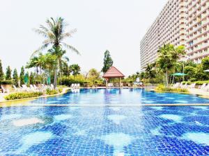 uma piscina num resort com palmeiras e edifícios em Sea View Beachfront Condos Pattaya Jomtien Beach em Praia de Jomtien
