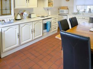 eine Küche mit weißen Schränken und einem Tisch und Stühlen in der Unterkunft Granary Cottage - Uk10994 in Eshott