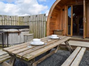 a wooden picnic table with two cups and plates on it at Withy Bottom-Uk1393 in Corney