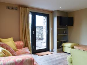 a living room with a couch and a sliding glass door at The Bothy in Beetham