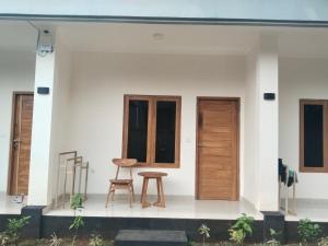 a white house with wooden doors and a stool at Nyuh Bali Guest House in Denpasar