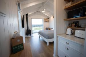 a bedroom with a bed and a kitchen with a counter at Banjos Cabin Gippsland - Luxury Eco Stay - King Bed, Pond Valley Views, Fireplace in Seaton