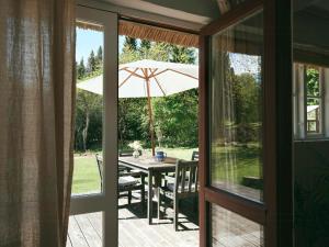 a patio with a table with an umbrella at Peaceful Forest Idyll In Timber House For Families in Jyderup +31 photos