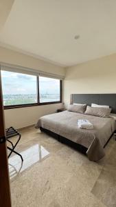 a bedroom with a large bed with a large window at Departamento con vista al mar-rio in Conchal