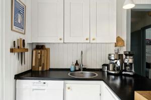 a kitchen with white cabinets and a sink at Cozy Summerhouse On Bornholm in Vester Sømarken
