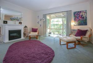 a living room with a fireplace and a purple rug at Mountain Thyme in Bright