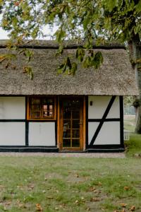 un fienile con porte bianche e tetto grigio di Romantic Nights Under The Thatched Roof a Scharnebeck