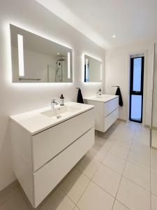 a white bathroom with two sinks and a mirror at Fjord Cabin With Panoramic Views In Rauma in Innfjorden