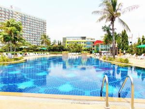 a large swimming pool with palm trees and buildings at Sea View Beachfront Condos Pattaya Jomtien Beach in Jomtien Beach