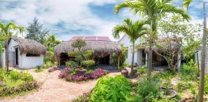 a house with a thatched roof and a garden at Red Flower Cottages Homestay in Hoi An