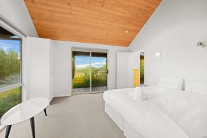 a white bedroom with a large bed and windows at Cozy 2BR Cottage Near Beach & Village Shops in Balnarring +7 photos