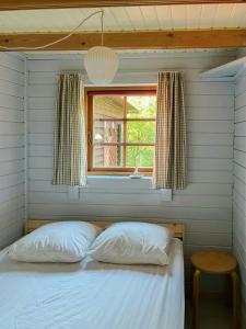 a bed with two pillows in a room with a window at Lillebo - Serene Cottage In Nature in Kolind