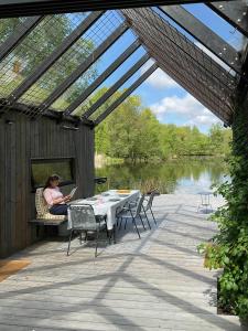een vrouw aan een tafel op een dek met een laptop bij Architect-Designed House Close To Hornbæk in Tikøb