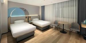 a bedroom with two beds and a table and chairs at City Comfort Inn Wuhan Guanggu Finance Port in Wuhan +259 photos