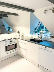 a white kitchen with a sink and a window at Summerhouse By The North Sea in Vestervig