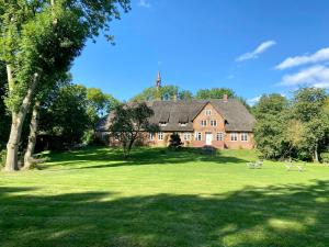 une grande maison en briques avec deux oiseaux dans l'herbe dans l'établissement Loft Under Thatch Retreat In Eiderstedt Nature, à Tetenbüll