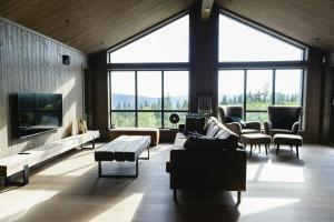 a living room with couches and a tv and large windows at Modern And Inviting Cabin In Valdres in Aurdal