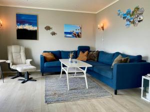 a living room with a blue couch and a table at Enjoy Views In Helgeroa, Near The Beach in Helgeroa