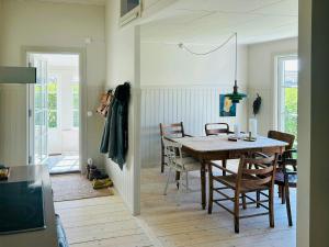 a dining room with a wooden table and chairs at Cottage With Glass Porch By Apelviken Beach in Varberg +19 photos